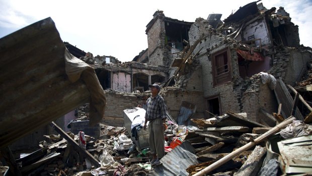A man stands on the debris of collapsed houses in Sankhu, Nepal.