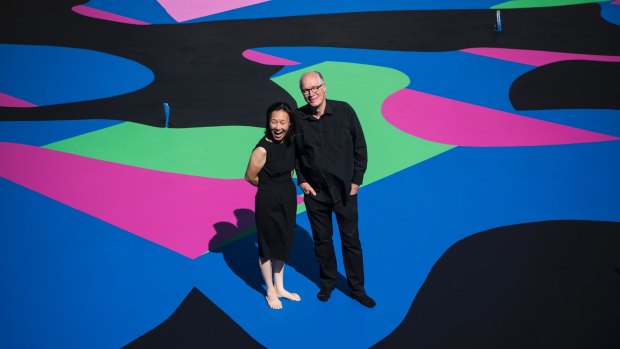 Architect and arts patron Corbett Lyon with his wife Yueji standing on Reko Rennie's <i>Visible Invisible</i>, painted on the base of his second Housemuseum of contemporary art in Kew.