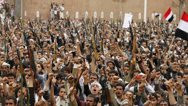 Houthi rebels hold up their weapons in the Yemeni capital, Sanaa.