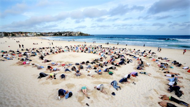 Protesters bury their heads in the sand at Bondi Beach to send a climate change message to Tony Abbott during the G20 Summit in Brisbane.