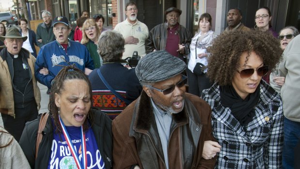 Spokane NAACP President Rachel Dolezal, right, link arms and sings 'We Shall Overcome' at a rally in downtown Spokane, Washington, responding to a racist and threatening package received by Dolezal in March. 