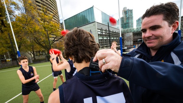 Melbourne Grammar Scott Whyte inserts a GPS tracking unit into a Year 7 footballer's jumper.