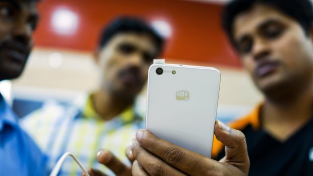 A store assistant demonstrates a smartphone to customers in Delhi.