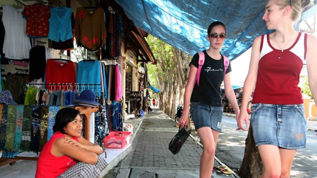 Tourists walk through the main shopping street in Bali.