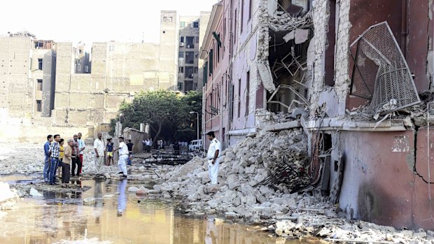 Policemen and onlookers stand at the base of the crumbled facade of the Italian consulate in Cairo.