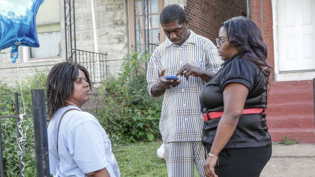 Barbara (left) and Dennis Ball-Bey, the parents of Mansur Ball-Bey, stand with their niece Shawnetta (right) on the steps where Mansur was shot in the back by police in St Louis, Missouri.