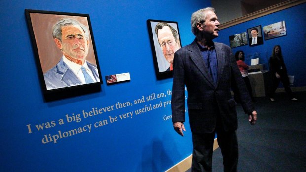 George W. Bush tours an exhibit of his paintings at his library in 2014.