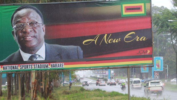 Traffic flows past a billboard with a portrait of Emmerson Mnangagwa.