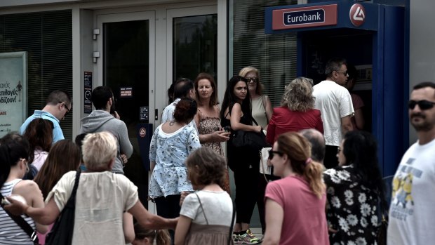 People queue at a national Bank of Greece ATM in central Athens.