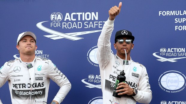 Lewis Hamilton celebrates taking pole while teammate Nico Rosberg watches on.