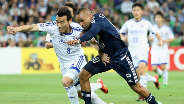 Archie Thompson of the Victory and Cho Won Hee of Suwon battle for the ball.