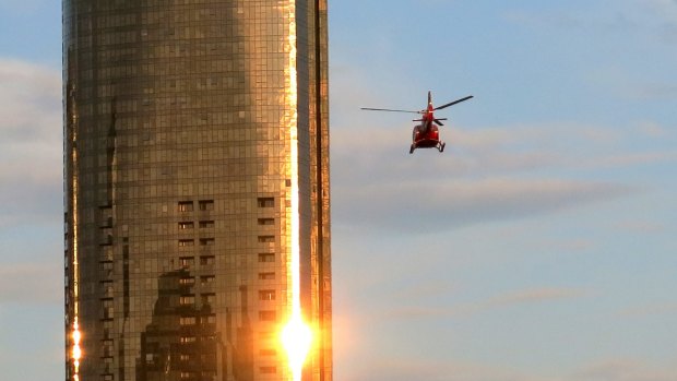 A helicopter flies through Melbourne skyscrapers along the Yarra River.