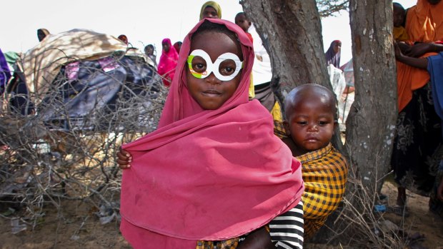 A young Somali girl displaced by drought wears mock spectacles cut from an antibiotics medicine box at a relief camp near the capital, Mogadishu, in March 2017.
