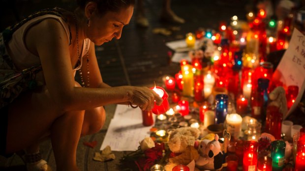 A woman lights up a candle at a memorial tribute to the victims of the vehicle attacks on Barcelona's historic Las Ramblas promenade.