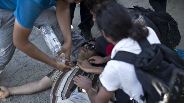 A man gets medical help after he was injured while trying to push through a police line in Tovarnik, Croatia on Thursda. More than 2000 men, women and children were stuck at the local train station 