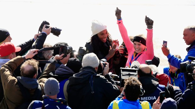 Caroline Wozniacki celebrates with Serena Williams as photographers take her picture.