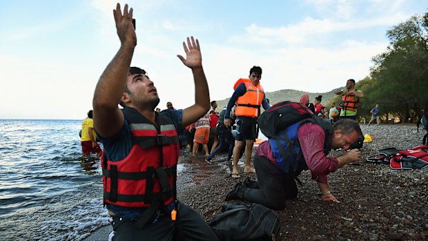 Scenes from a crisis: Men overwhelmed with emotion collapse onto the shore, praying moments after arriving on the Greek island of Lesbos by rubber dinghy with about 45 refugees from Syria, Iraq and Afghanistan after a three-hour journey from Turkey last month.