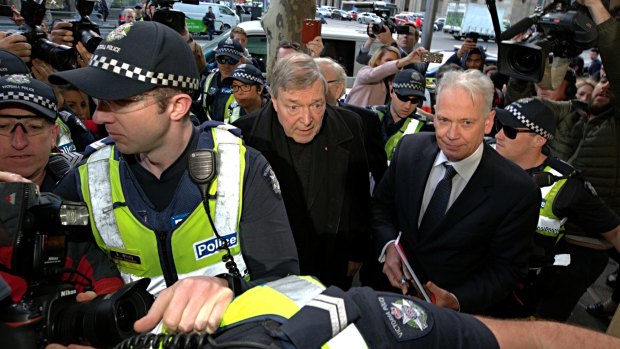 Cardinal George Pell makes his way through the throng of media, with lawyer Paul Galbally by his side.