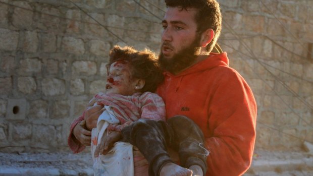 Pulled from the wreckage: A man carries a Syrian child to safety following airstrikes on residential areas of Aleppo, Syria in November. 