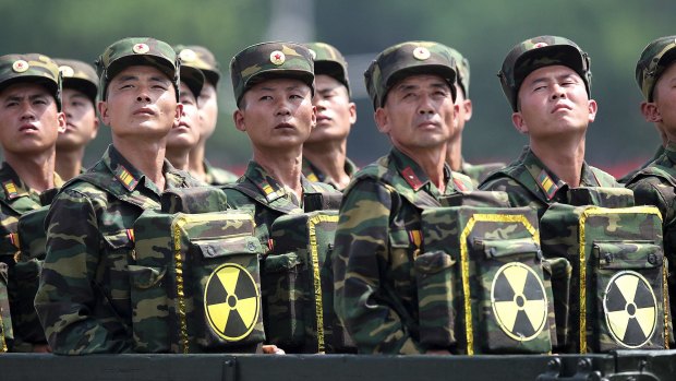 North Korean soldiers look towards their leader Kim Jong-un during a military parade, carrying packs marked with the nuclear symbol.