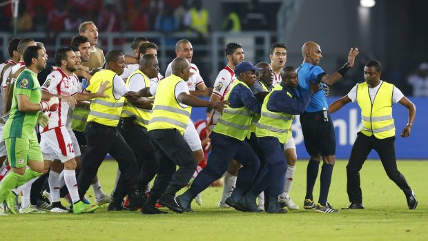 Referee Seechurn Rajindraparsad is escorted from the pitch by security.