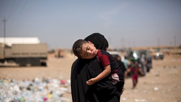 A child sleeps on his mother's shoulder after a perilous journey on foot to flee heavy fighting between Iraqi forces and Islamic State militants in Mosul.