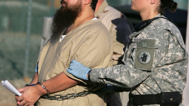 A shackled Guantanamo Bay detainee is transported by a female guard, front, and male guard, behind, away from his annual Administrative Review Board hearing at Camp Delta detention centre 