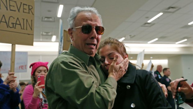 Iranian green card holder Shima Behgooy, right, cries on the shoulders of her father-in-law Ahmad Behgooy, a native of Iran who is now a US citizen, after she was released at Dallas-Fort Worth International Airport.