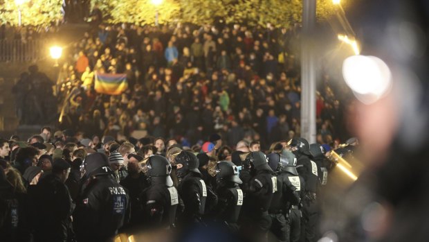 German police officers stand in a line in front of protesters against a demonstration marking the first anniversary of Pegida in Dresden on Monday.