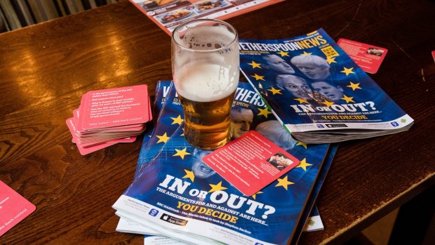 A pint of ale sits atop of a pile of magazines, featuring articles about the EU referendum, and near to beer mats arguing for a Brexit in a London pub. 