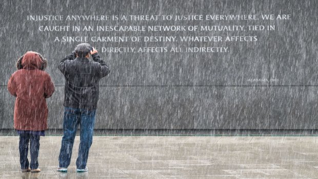 Visitors to the Martin Luther King, Jr Memorial in Washington stop to photograph the quotes etched into the memorial's back wall while it snows in the Nation's Capital.