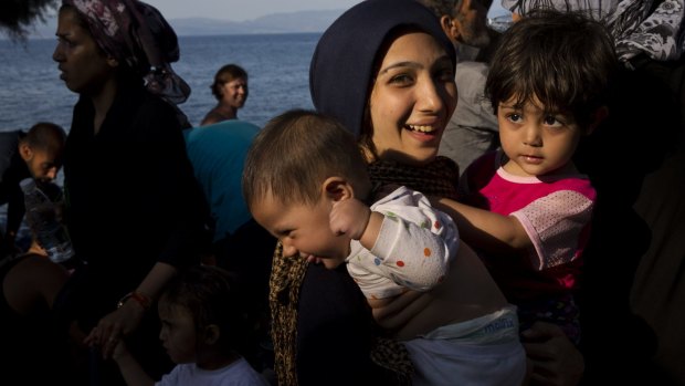 A migrant holds two children as they arrived on a dinghy after crossing from Turkey to Lesbos island, Greece, on Tuesday.