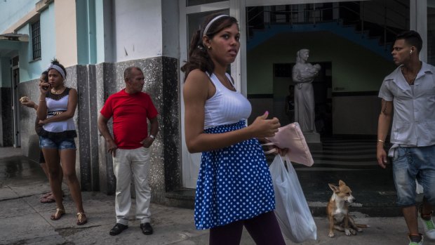 A pregnant woman waits for family members outside a hospital in Havana. Many young Cubans are avoiding having children.