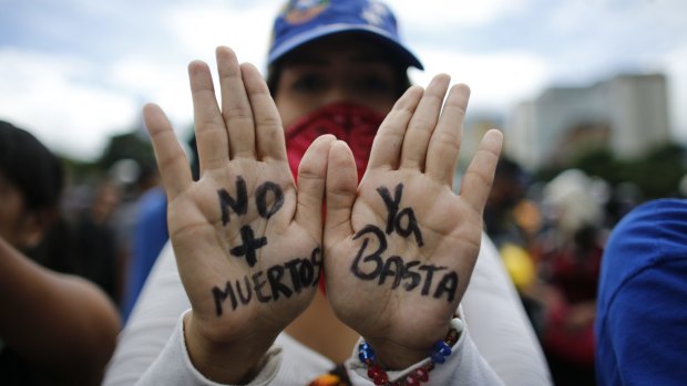 A demonstrator with "No More Deaths" and "Enough" written in Spanish on her hands joins a protest against the government of President Nicolas Maduro, in Caracas.