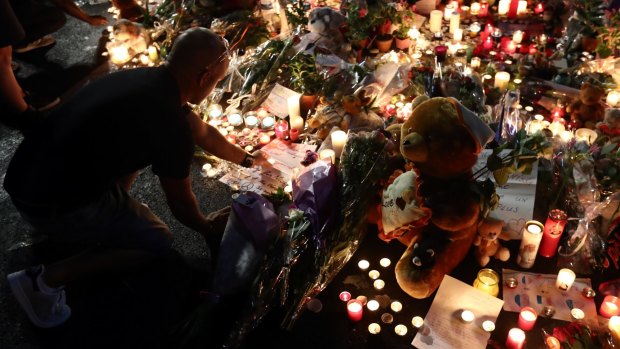 A man places a candle among flowers and tributes in Nice.
