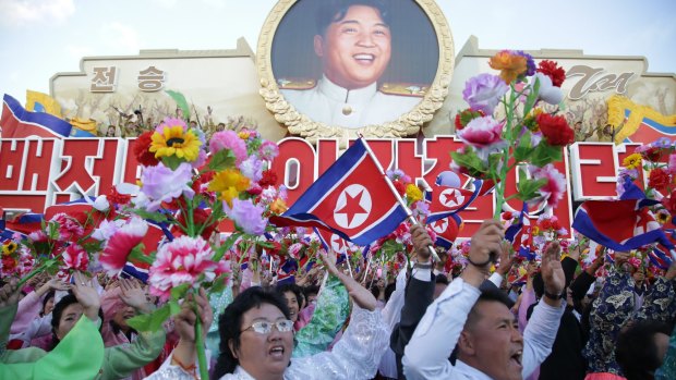 North Koreans cheer beneath an image of Kim Il-sung as they parade in Pyongyang.