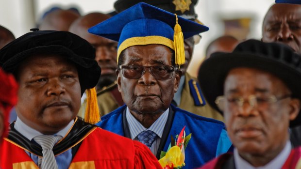 Zimbabwe's President Robert Mugabe, centre, arrives to preside over a student graduation ceremony at Zimbabwe Open University.