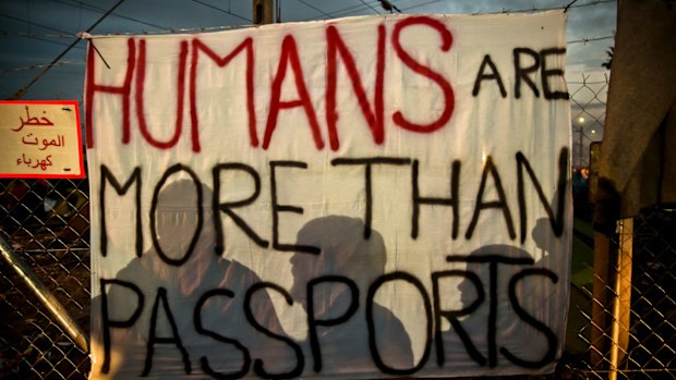 People cast shadows on a banner at the northern Greek border station of Idomeni.