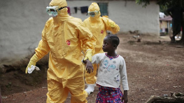 A young girl is taken to an ambulance after showing symptoms of Ebola during the 2014 outbreak in Liberia.
