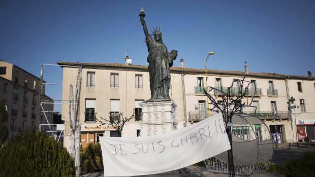 A "Je Suis Charlie" banner hangs in front of a replica Statue of Liberty in Lunel.