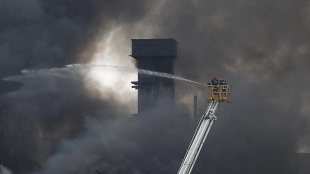 Firefighters on a ladder spray water to put out the fire at a packaging factory in Tongi industy area outside Dhaka.