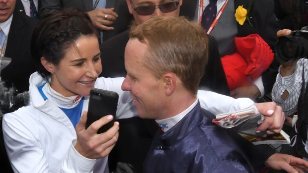 Michelle Payne, last year's Melbourne Cup winning jockey, hands the phone to her brother-in-law Kerrin McEvoy who rode Almandin to win the Melbourne Cup on Tuesday.