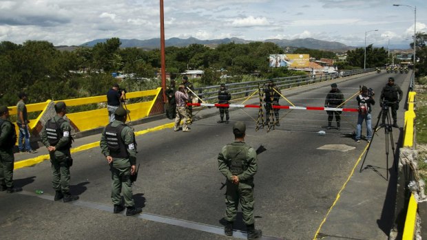 Venezuelan National Guards (bottom) stand in front of Colombian soldiers on the Simon Bolivar international bridge, on the border with Colombia.