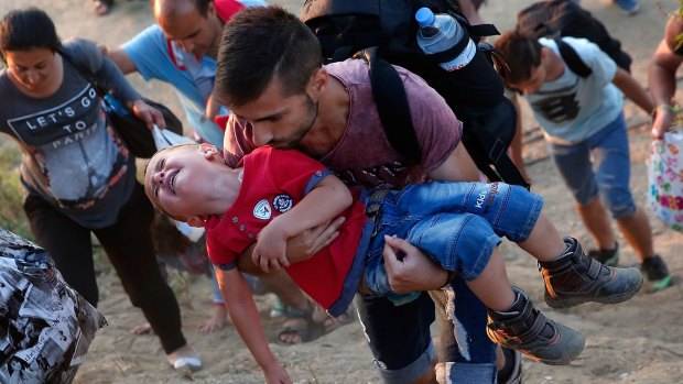 A young Syrian boy cries as his father carries him up a steep hill as they walk to a border crossing on the Greek and Macedonian border. 