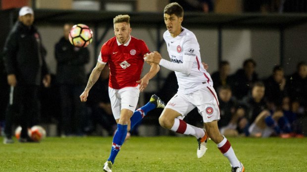 Canberra FC's Thomas James and Wanderers player Jonathan Aspropotamtis fight for the ball.