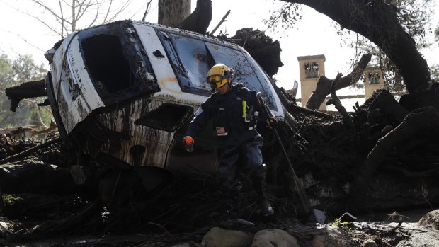 Crews look for survivors near a car trapped under debris in Montecito.