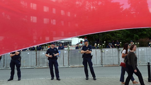 A big Polish national flag is spread by protesters in front of the parliament as police officers guard the building in Warsaw on  July 18.
