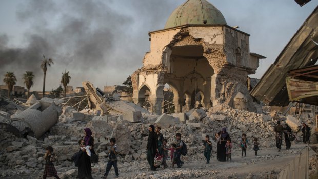 Fleeing Iraqi civilians walk past the heavily damaged al-Nuri mosque as Iraqi forces continue their advance against IS this week.