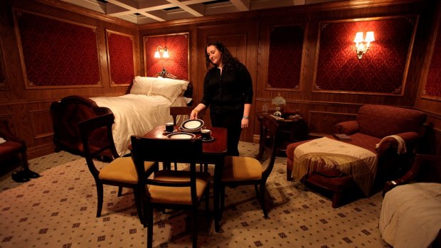 A woman positions a plate in a recreation of a first class cabin on the Titanic in an exhibition in London.