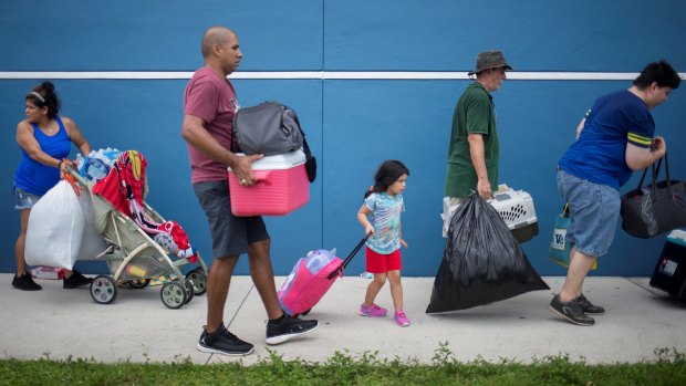 Residents carry their belongings into a shelter ahead of the downfall of Hurricane Irma in Estero, Florida.